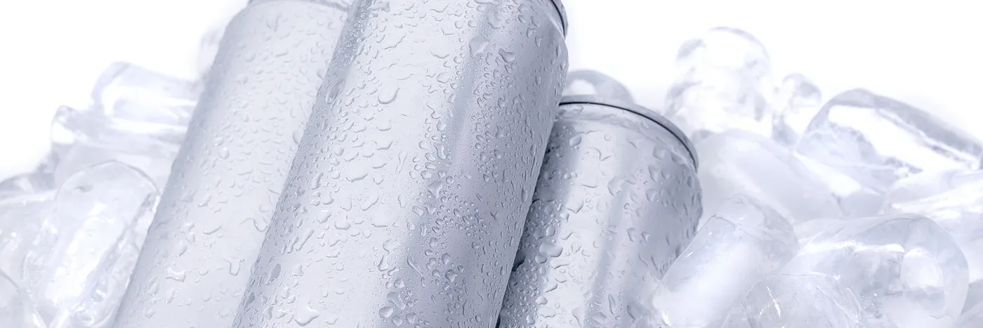 Three plain unbranded aluminium drink cans resting on crushed ice against a white background