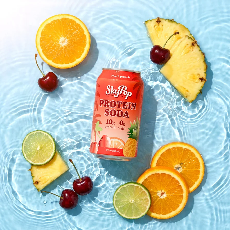 SkyPop Fruit Punch protein soda can floating in water with orange, lime and cherry slices