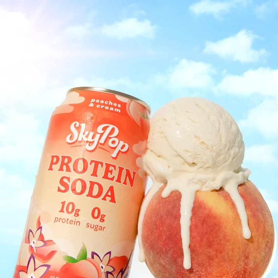 SkyPop Peaches and Cream protein soda can beside a fresh peach topped with a scoop of ice cream